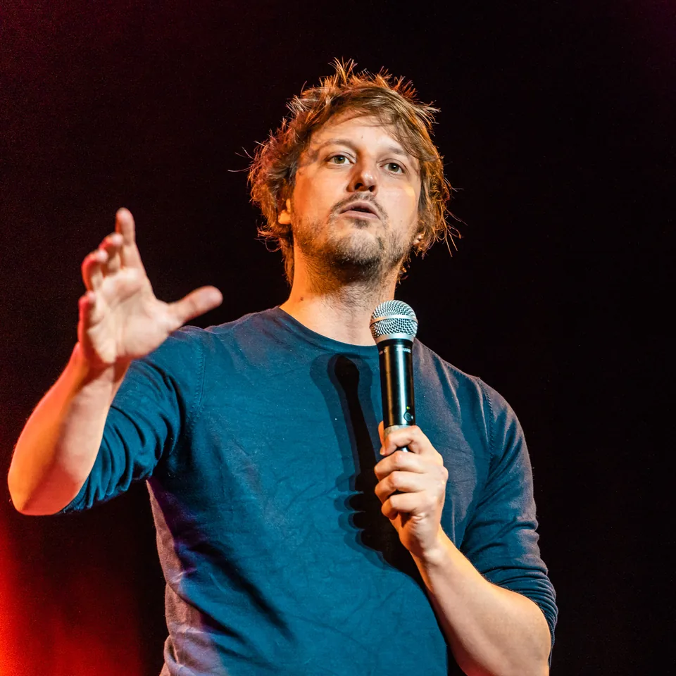 Yvain sur scène, de face, micro à la main, au festival d’humour de Brides-les-Bains.